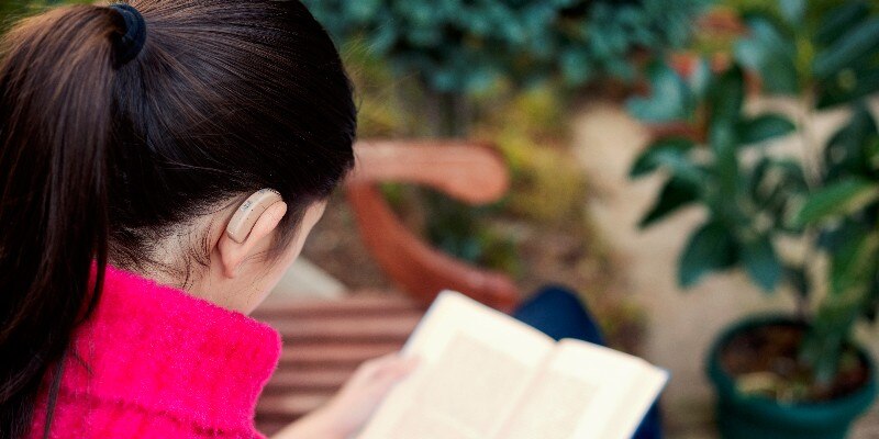 Woman wearing a hearing aid reading a book