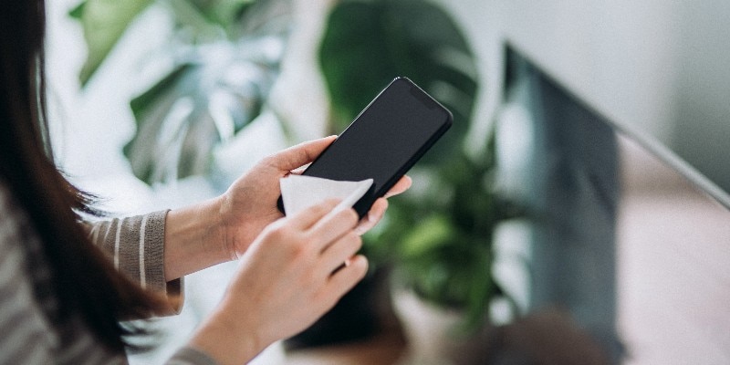 a woman wiping off her cell phone to clean it