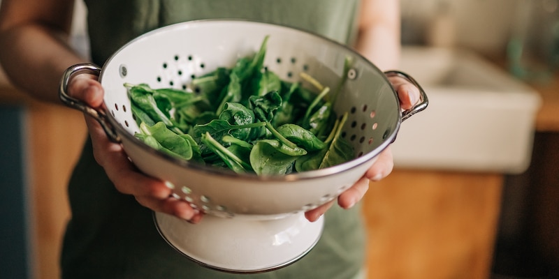 woman holding spinach source of B vitamins biotin