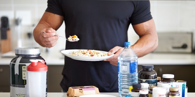 a muscular man with his supplements eating breakfast