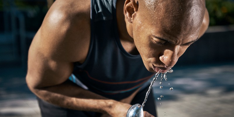 African American man drinking from a water fountain