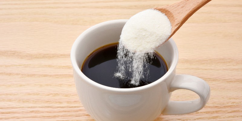 A wooden spoon pouring collagen into coffee