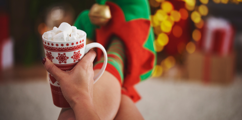 Person holding festive mug with their feet up