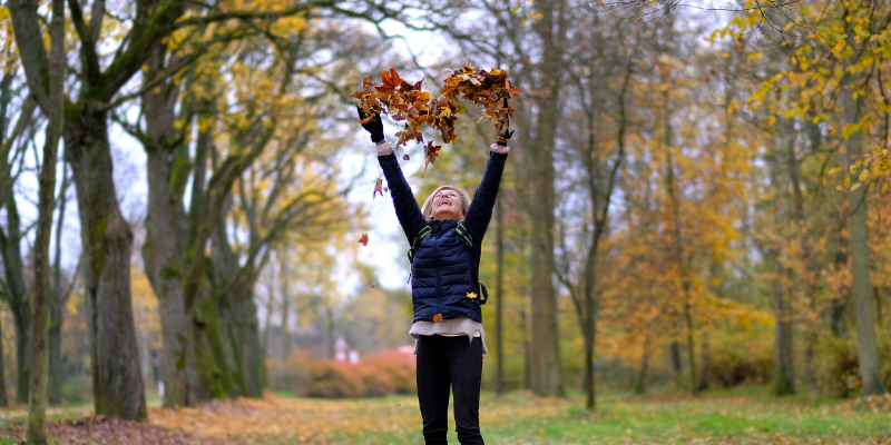Woman throwing leaves in the air in a heart shape heart health