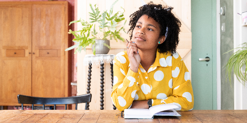 African American woman in a yellow polka dot shirt journaling during her morning routine